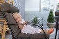 Little girl is resting in a large chair. Child is sitting in chair in cafe