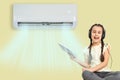 little girl resting under air conditioner on colored wall at home Royalty Free Stock Photo