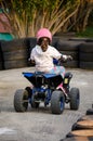 Little Girl Rides a Motorcycle ATV with Four Wheels. Outdoor Activity for Kid on an Electric Racing Quad Bike Machine