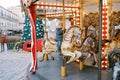 Little girl rides a toy horse on a carousel at a fair near a decorated Christmas tree near an old house Royalty Free Stock Photo