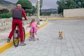 Little girl riding a bike with dad and with a chihuahua dog outdoors. Royalty Free Stock Photo