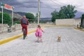 Little girl riding a bike with dad and with a chihuahua dog outdoors.