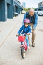 Little girl riding a bike with her father\'s hepl. Father teaching his little daughter to ride a bike Royalty Free Stock Photo