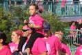 Little girl riding on fathers shoulders breast cancer walk