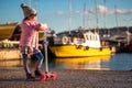 Little girl riding scooter outdoor near sea harbour Royalty Free Stock Photo