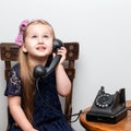 A little girl is ringing on the old phone.