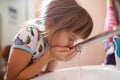 Little girl rinses her mouth with water after brushing your teeth in the bathroom