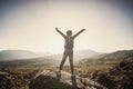 Little girl on a rock in the mountains. The child stretched out his arms towards the sun.