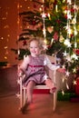 Little girl in rocking chair under Christmas tree Royalty Free Stock Photo