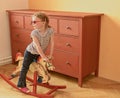 Little girl on rocking horse. Small girl wears red glasses.