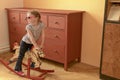 Little girl on rocking horse. Small girl wears red glasses.