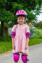 A little girl roller skates in full protection on a village road. Royalty Free Stock Photo