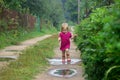 Little girl in rubber boots runs through muddy puddles along a country sandy road after rain Royalty Free Stock Photo