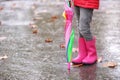 Little girl with rubber boots and umbrella after rain, focus of legs Royalty Free Stock Photo