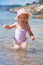 Little girl running beach shore splashing water