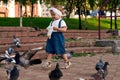 Little girl running near doves, chasing pigeons, happy child with smiling face. Kid is feeding pigeons in city park Royalty Free Stock Photo