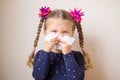 The little girl with runny nose blows into handkerchief.