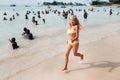 A little girl runs along a tropical beach with locals on the island of Mauritius.a girl on the beach of the Indian ocean and