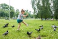 A little girl runs for pigeons.Baby Girl Chasing Pigeons In Outdoors City Park. cheerful happy childhood, runs laughing Royalty Free Stock Photo