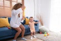 A little girl runs and plays with a small soap bubble that his mother blows for him to play with. In the living room Royalty Free Stock Photo