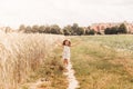 A little girl runs through a wheat field. The girl has fun and laughs with delight. Field with ripe ears of corn at sunset Royalty Free Stock Photo