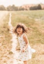 A little girl runs through a wheat field. The girl has fun and laughs with delight. Field with ripe ears of corn at sunset Royalty Free Stock Photo