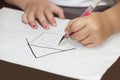 Little girl's hands with ballpen drawing a house Royalty Free Stock Photo