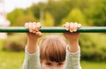 A little girl`s hands are holding onto the rung of a ladder on a playground, close-up. A little girl is training, suspended on a Royalty Free Stock Photo