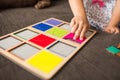 Little girl`s hands playing with a wood mosaic on a sofa. Educational games. Montessori Preschool early develop