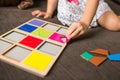 Little girl`s hands playing with a wood mosaic on a sofa. Educational games. Montessori Preschool early develop