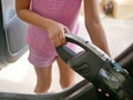 Little girl`s hands using a portable handheld vacuum cleaner to clean up a car