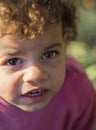 A little girl with sad big eyes and curly hair looks up at the camera in Greece Royalty Free Stock Photo