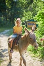 Little girl in the saddle riding on a donkey, in contact farm zoo Royalty Free Stock Photo