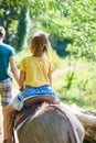 Little girl in the saddle riding on a donkey, in contact farm zoo Royalty Free Stock Photo