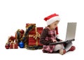 Little girl in Santa Claus cap with a laptop and Christmas gifts Royalty Free Stock Photo
