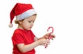 Girl in santa claus hat with candy cane lollipop for christmas, isolated on white. sweet gifts for children for the new year Royalty Free Stock Photo