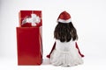 Little girl with Santa Claus hat sitting on her back next to some red presents on a white background. christmas concept Royalty Free Stock Photo