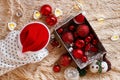 Little girl in Santa Claus red hat is playing with Christmas decorations and Christmas lights on a beige plaid, top view. Royalty Free Stock Photo