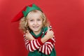 Little girl in Santa elf helper costume on bright red vivid color background Royalty Free Stock Photo