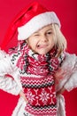 Little girl in santa hat and scarf on red background Royalty Free Stock Photo