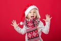 Little girl in santa hat and scarf on red background Royalty Free Stock Photo