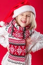 Little girl in santa hat and scarf on red background Royalty Free Stock Photo