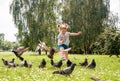 Little girl scares pigeons fun game summer. ecology, runs on the grass in the city park outdoors, lifestyle
