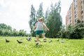 Little girl scares pigeons fun game summer. ecology, runs on the grass in the city park outdoors, lifestyle Royalty Free Stock Photo