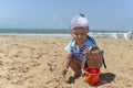 A little girl in a scarf playing on the sandy beach