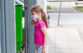 Little girl, school age child in protective anti viral face mask entering a shop, convenience store alone, on her own Royalty Free Stock Photo