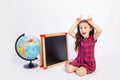 Little girl school girl 7 years old sitting in a red dress at a chalkboard with a globe on a white isolated background laughing, Royalty Free Stock Photo