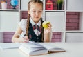 Little girl  school student sitting at her desk, writing home task  and eating  out an apple Royalty Free Stock Photo