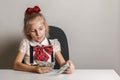 A little girl in a school uniform is counting money - hundred-dollar bills Royalty Free Stock Photo