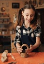 A little girl sculpts a basket of clay